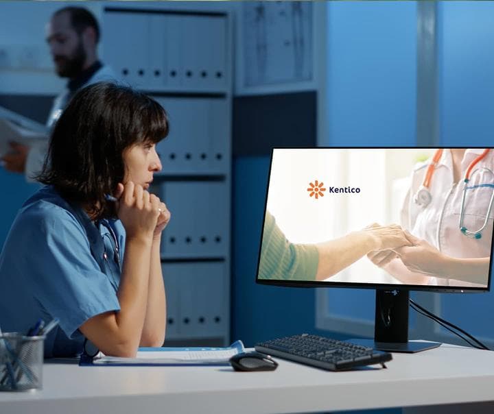 Doctor looking at a computer with Kentico logo
