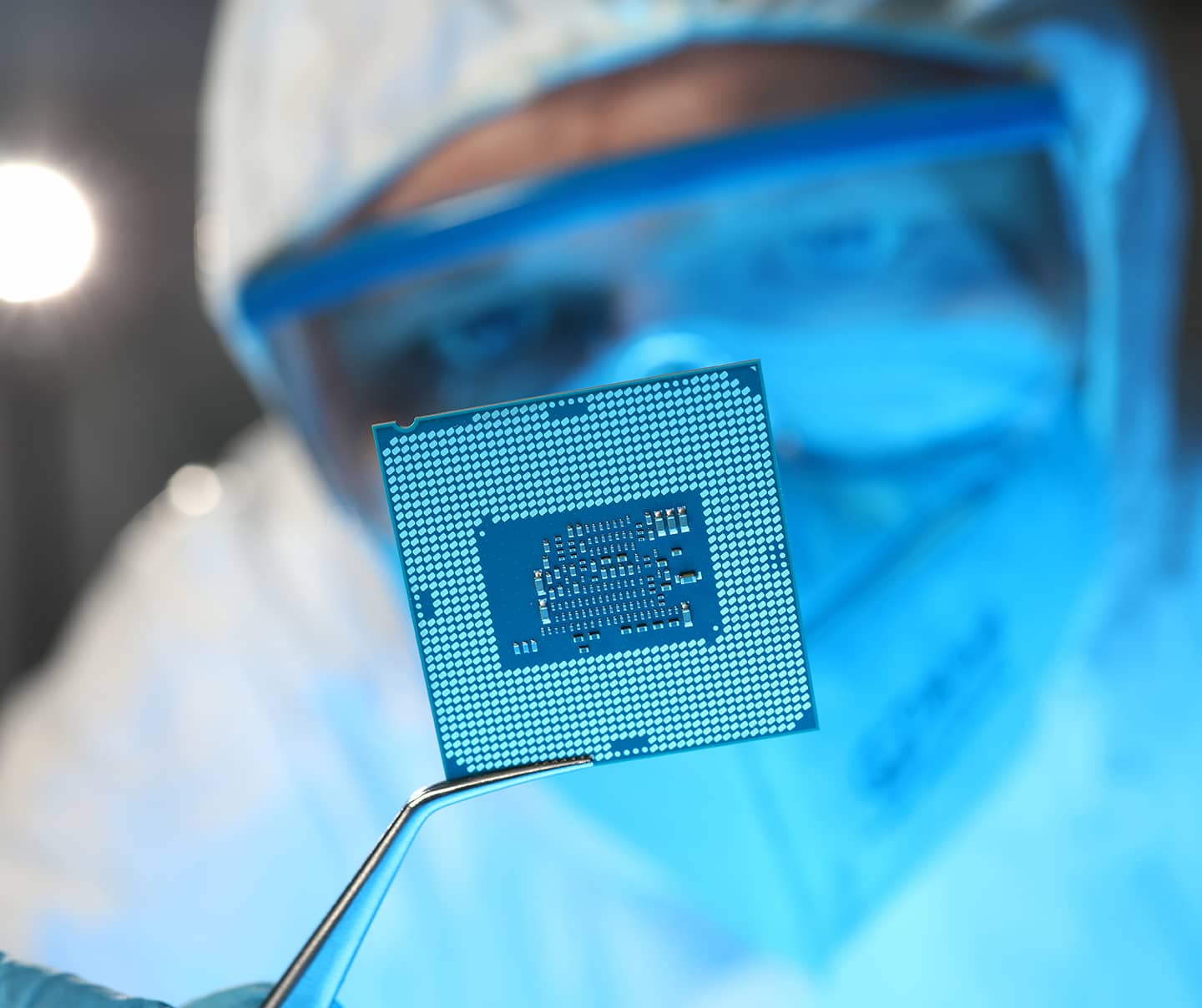Man in protective suit and glasses holding semiconductor chip for a computer