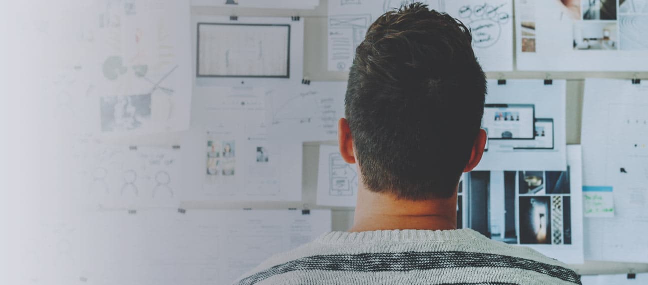 man looking at bulletin board with website mockups
