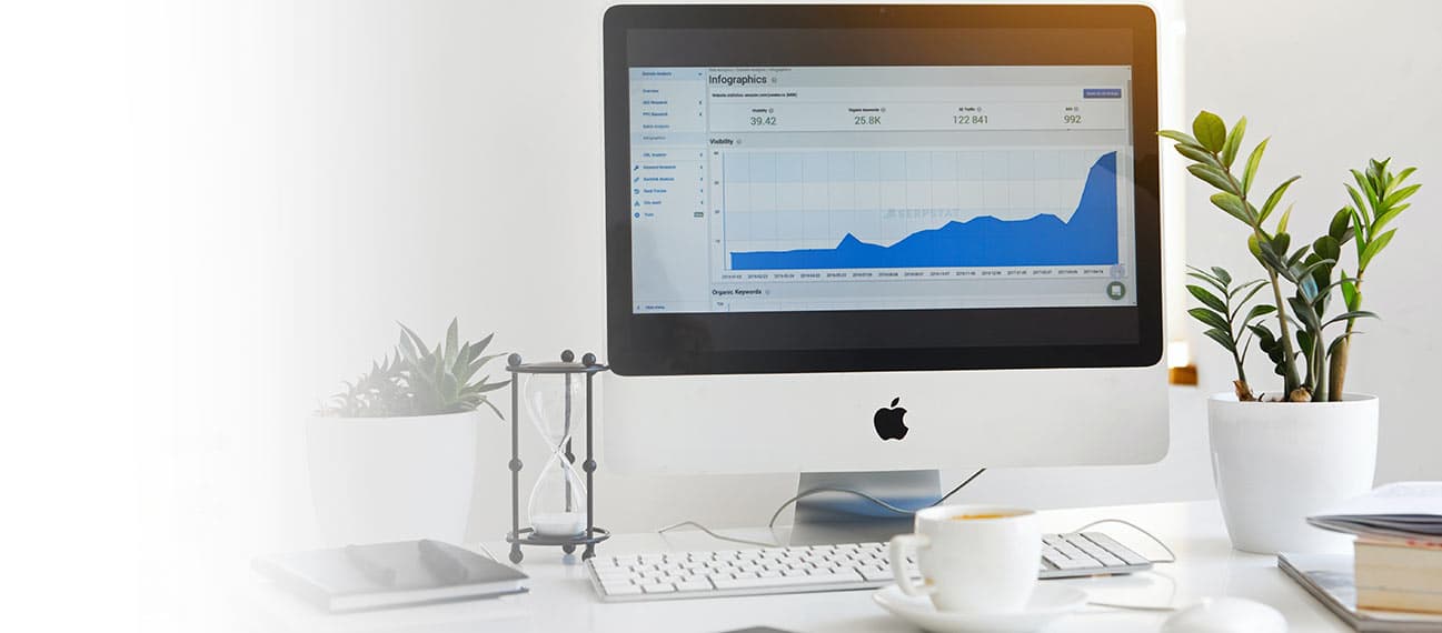 Computer on desk displaying upward-trending graph