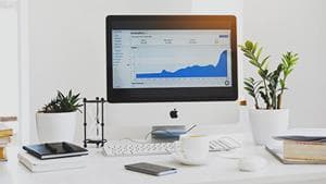 Computer on desk displaying upward-trending graph