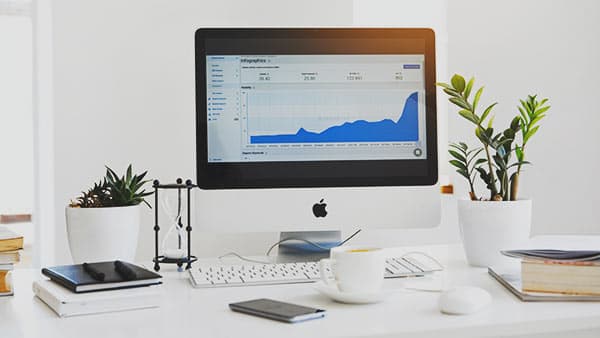 Computer on desk displaying upward-trending graph