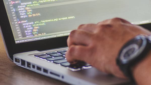 programmer's hand on laptop keyboard