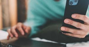 Person using both laptop and mobile phone