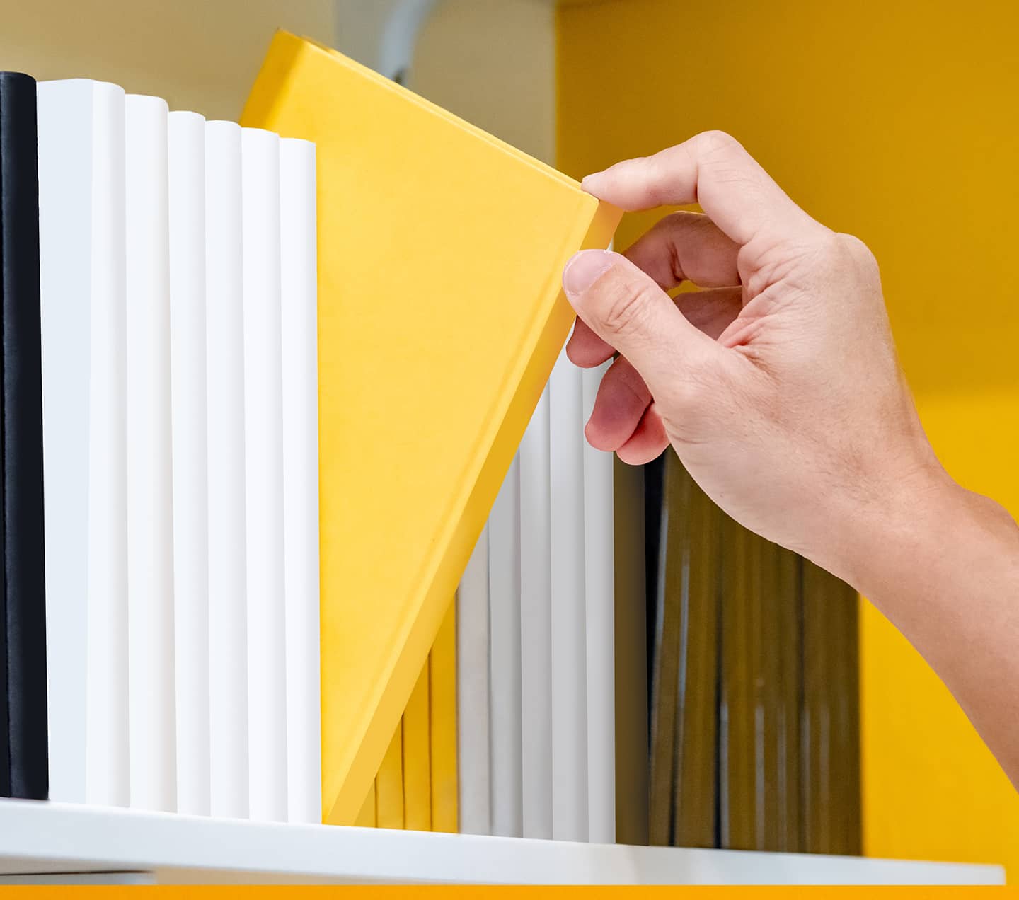 Person selecting a book in a shelf