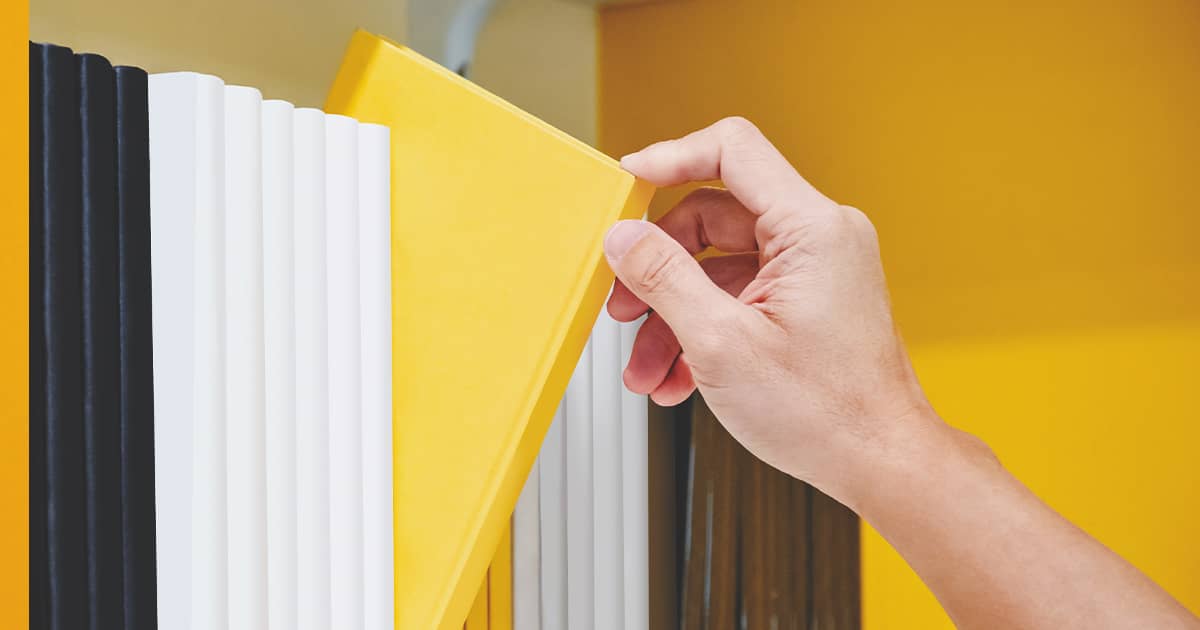 Person selecting a book in a shelf