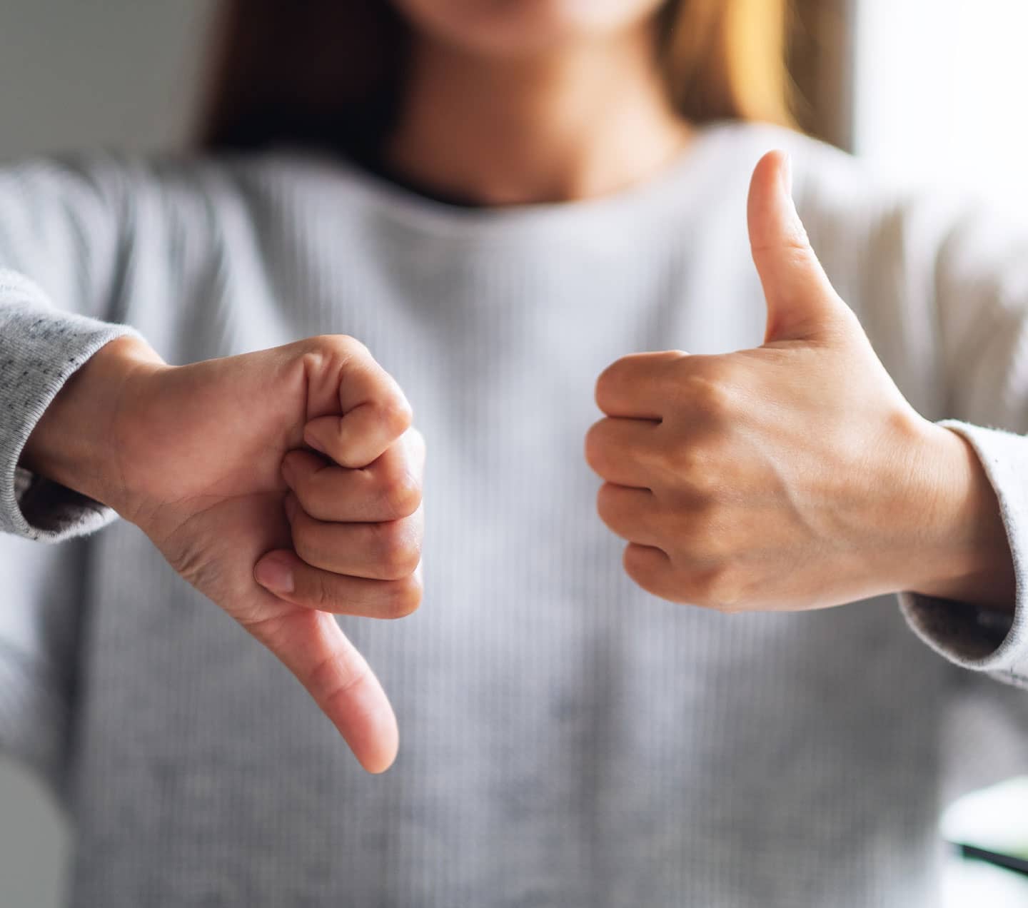 Woman making thumbs up and thumbs down representing positive or negative feedback