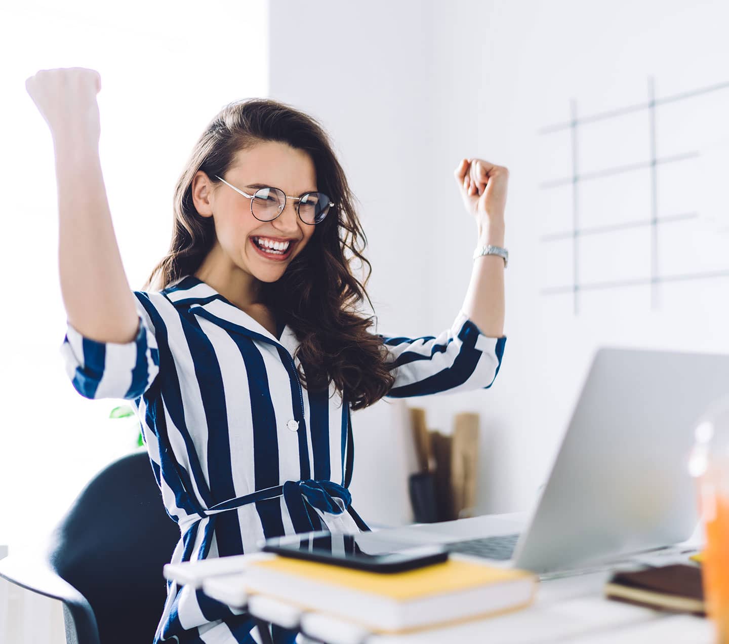 Woman sitting at a desk celebrating success