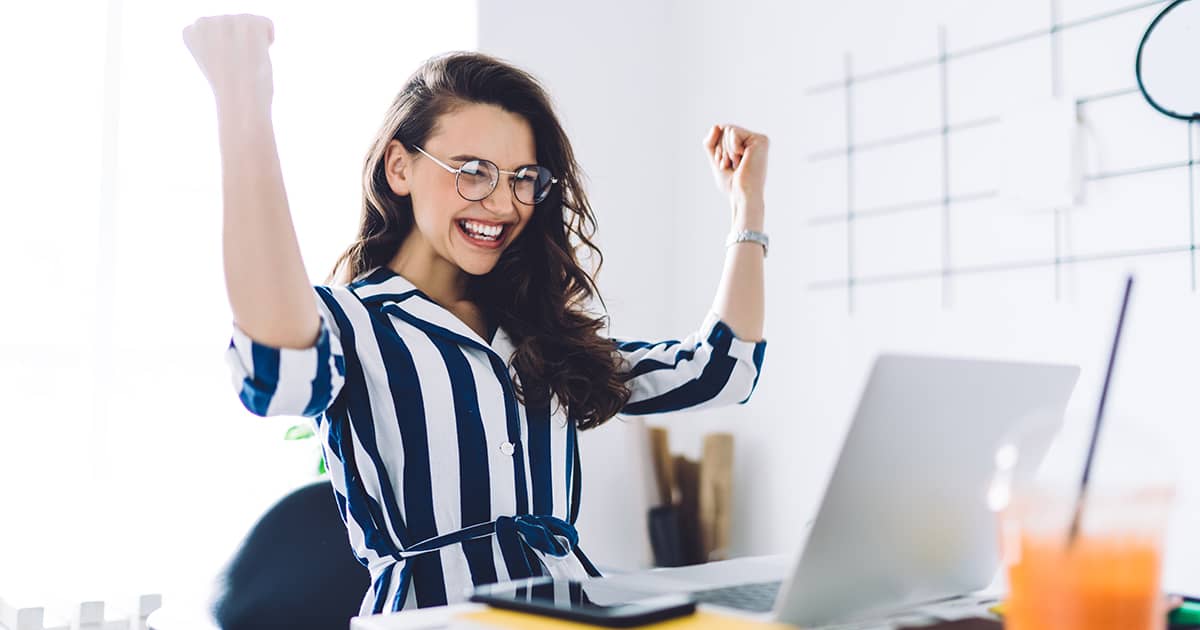 Woman sitting at a desk celebrating success