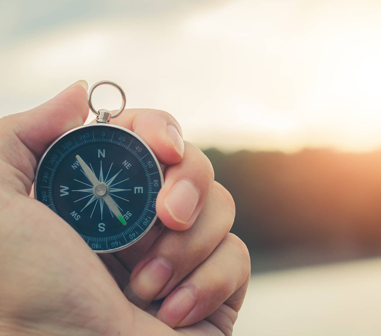 Compass on a mountain at sunset sky.