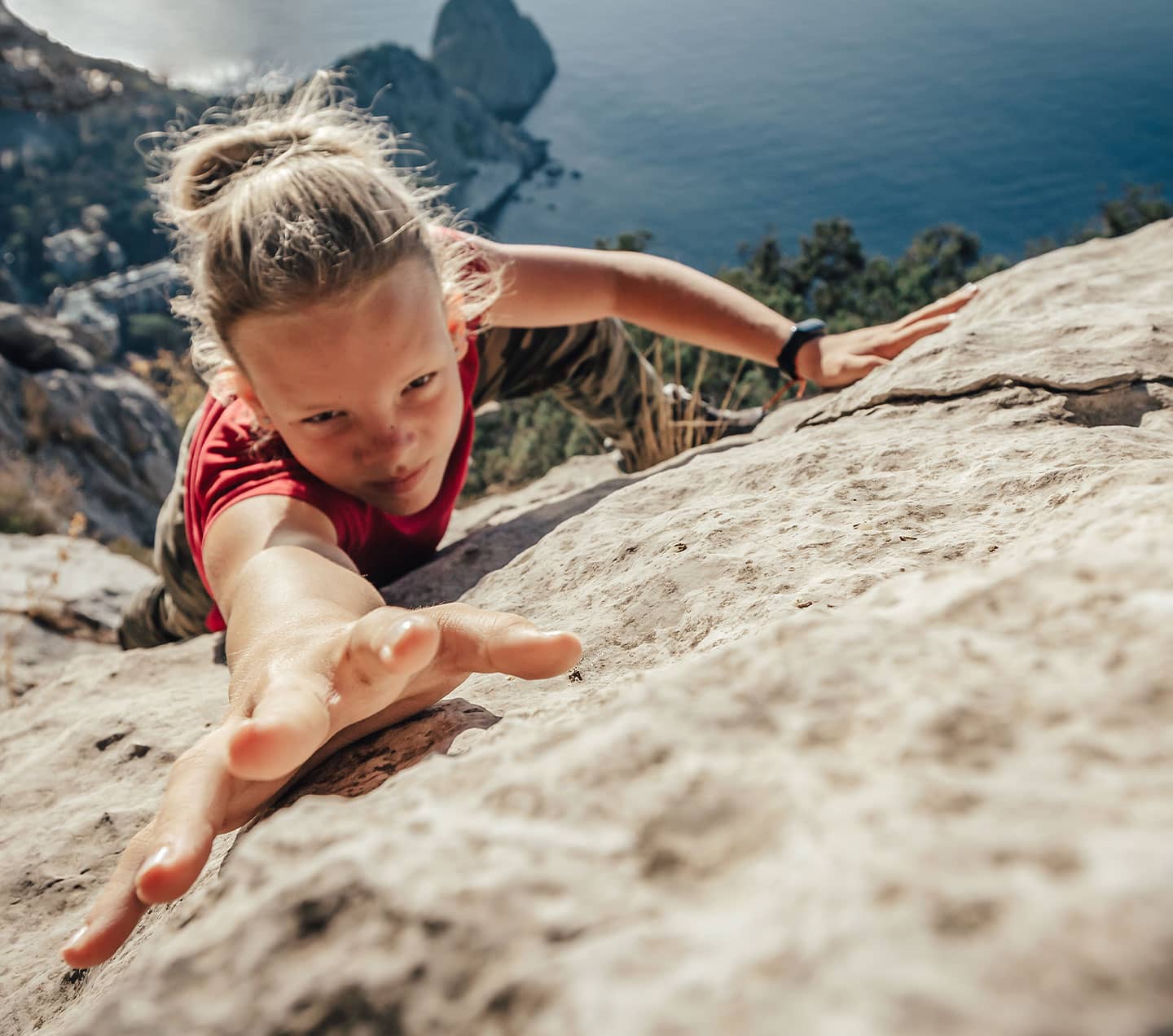 Young woman climber climbing up a stone wall overcoming obstacles