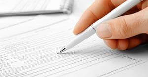 Hand holding a pen, filling out a form