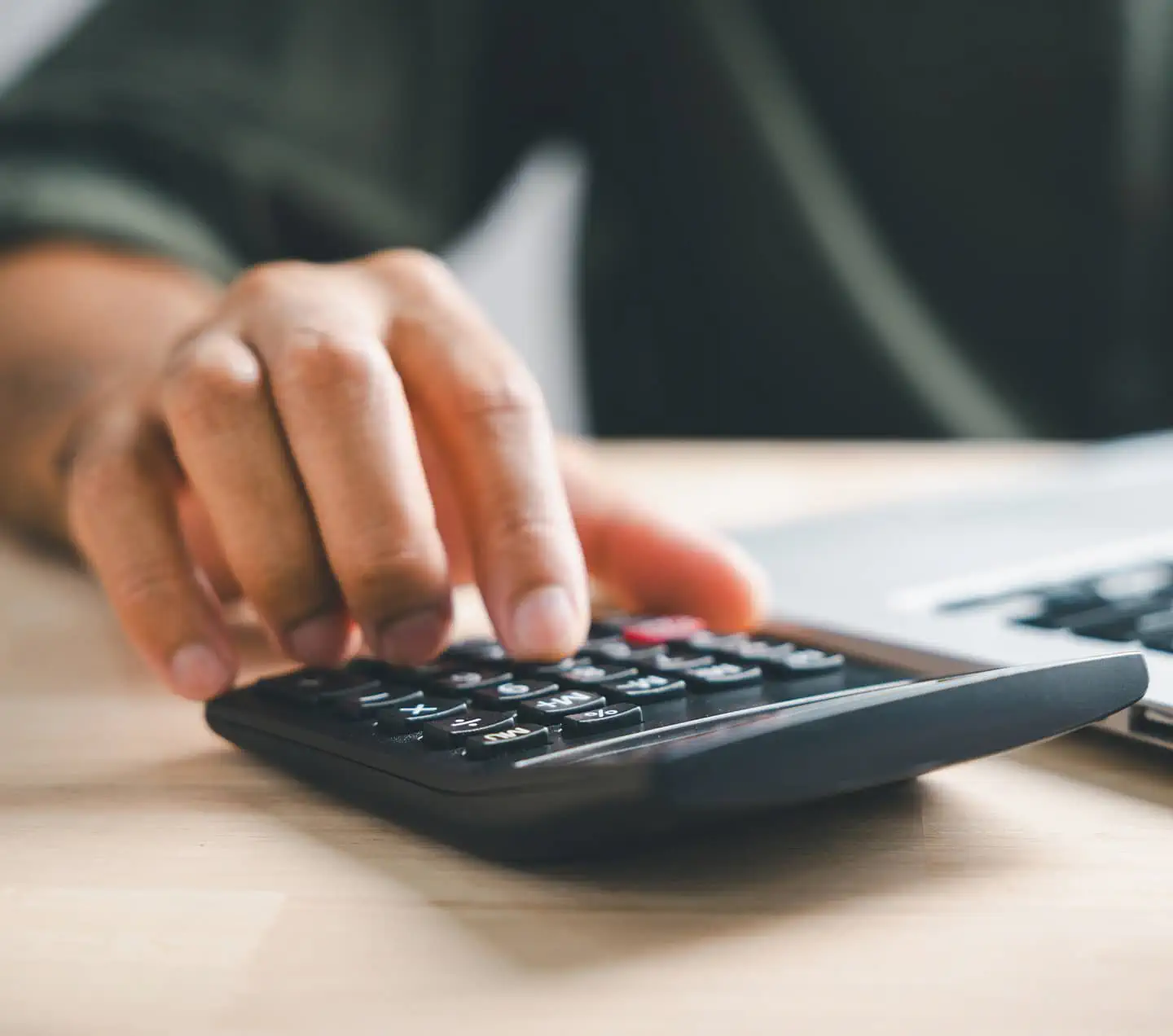 Hand entering budget information on calculator
