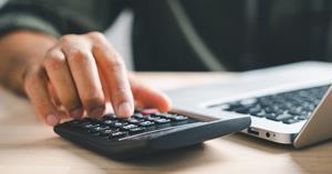 Hand entering budget information on calculator