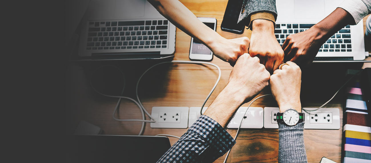 Team bumping fists over desk