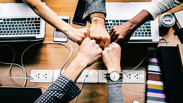 Team bumping fists over desk