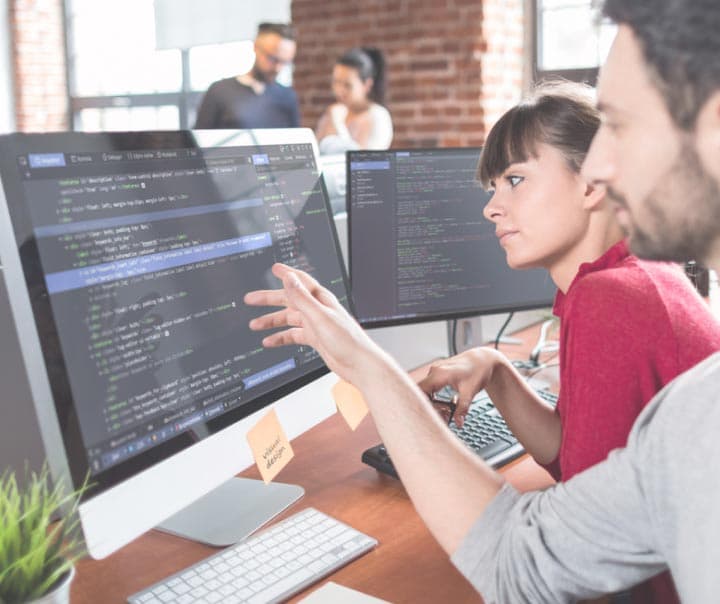 Man and woman in office reviewing Sitecore code